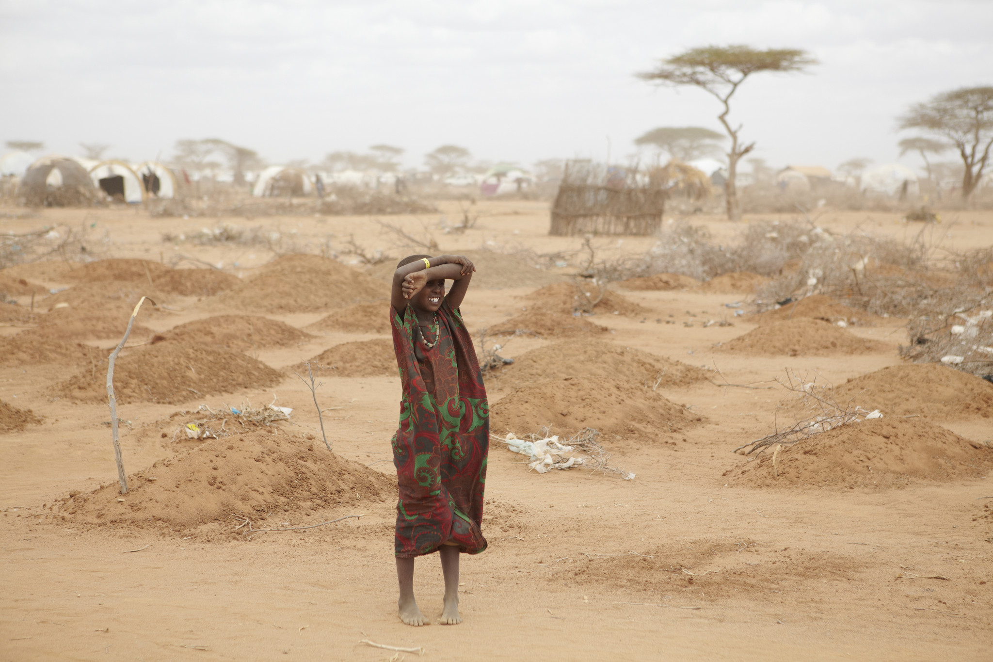 A young girl stands amid the freshly made graves of 70 children many of whom died of malnutrition. Dadaab refugee camp.